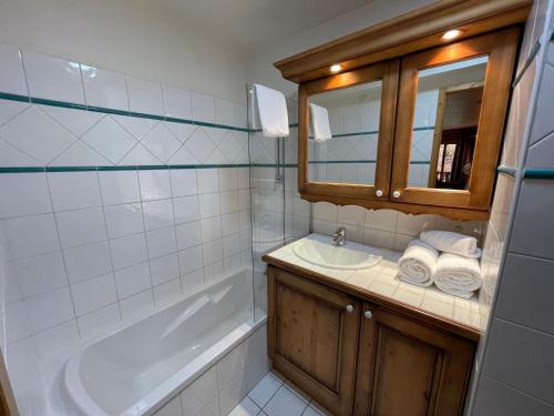 a bathroom with a sink and a tub and a mirror at Chalet Les Trappeurs in Les Carroz d'Araches