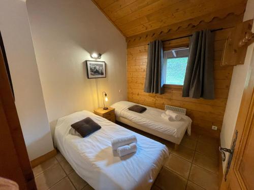 Duas camas num pequeno quarto com uma janela em Chalet Les Trappeurs em Les Carroz d'Arâches