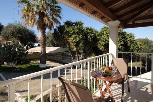 a table and chairs on a porch with palm trees at House Belelis in Afionas