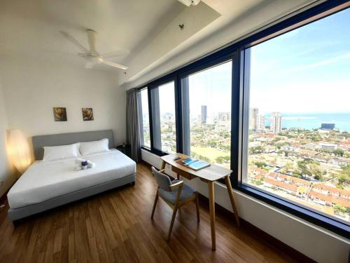 a bedroom with a bed and a desk and large windows at LS Tropicana 218*Sea View*1BR*Georgetown*King Bed in George Town