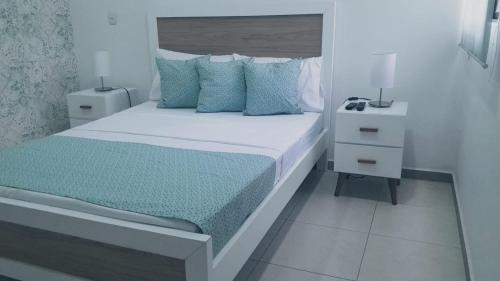 a white bedroom with a bed with blue pillows at Relax de Ensueño in La Tebaida