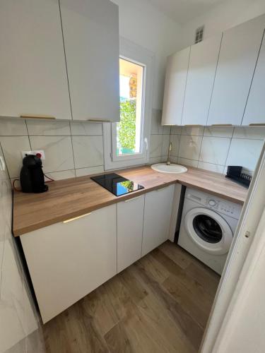 une cuisine avec un évier et une machine à laver dans l'établissement Appartement ensoleillé à Ajaccio, à Ajaccio