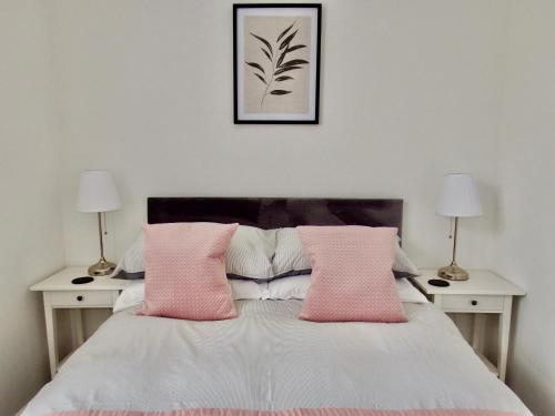 1 dormitorio con 1 cama con almohadas rosas y 2 mesas en Newly Renovated 3 Bedroom Victorian Detached House, en Bournemouth