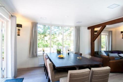 a living room with a dining room table and a couch at Familiehuis De Erica - 12 p in Otterlo