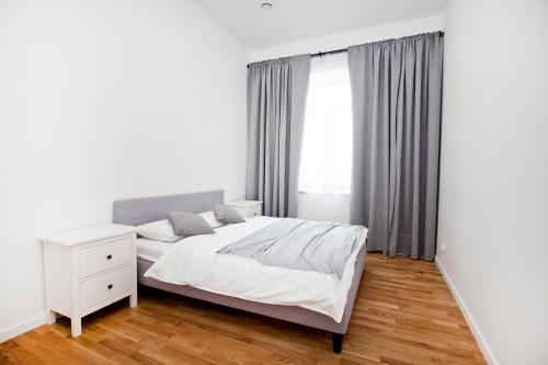 a white bedroom with a bed and a window at Apartamenty LAGOM in Siedlce