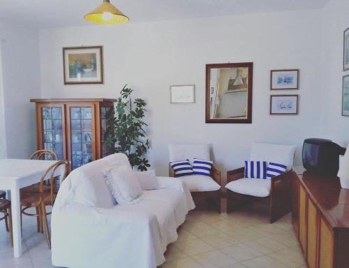 a living room with two white chairs and a table at Le case dei Venti in Tanaunella