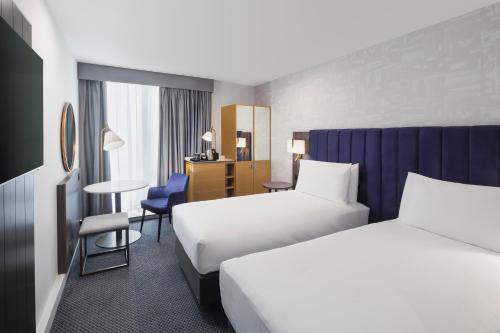 a hotel room with two beds and a desk at DoubleTree by Hilton Manchester Piccadilly in Manchester