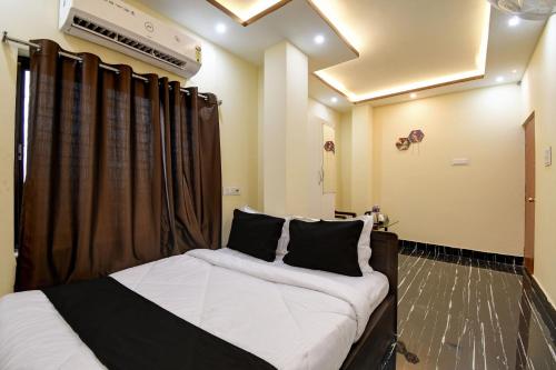 una camera da letto con un letto con lenzuola bianche e cuscini neri di OYO Chilli Pepper Hotel and Restaurant a kolkata