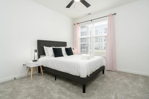 a white bedroom with a large bed and a window at Corporate Housing by MGM in Whitestown