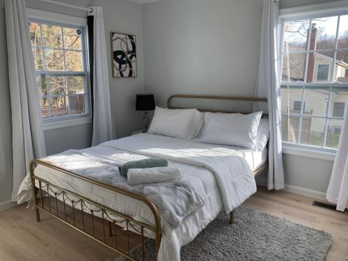 a bedroom with a bed with white sheets and windows at Silver Spring Serene 2BR 2BA, Nature And Access in Silver Spring