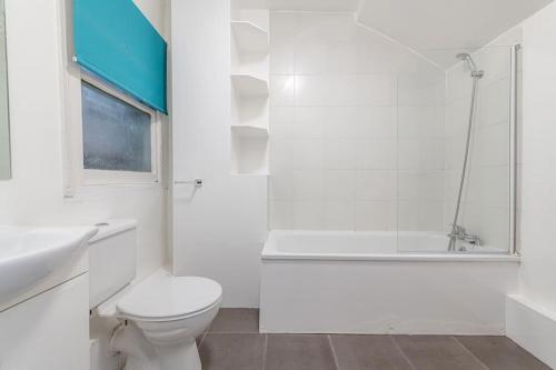 a white bathroom with a toilet and a bath tub at Central Muswell Hill- One Bed in London