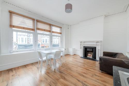 een woonkamer met een tafel en stoelen en een open haard bij Central Muswell Hill- One Bed in Londen