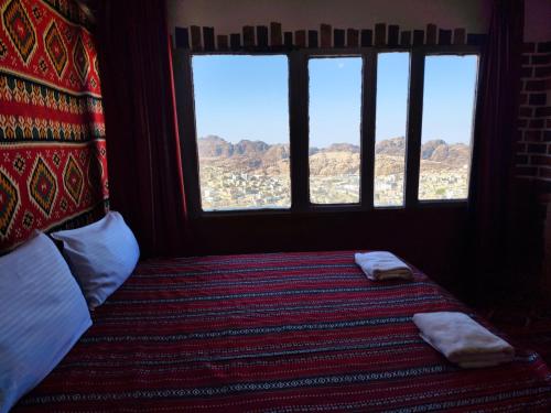 um quarto com uma cama com duas almofadas e duas janelas em Rocky Mountains Hotel em Wadi Musa