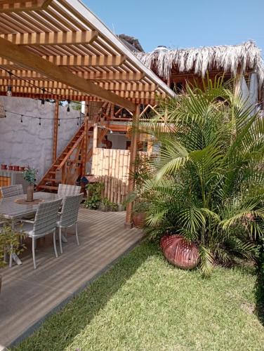 una terraza de madera con mesa y sillas bajo una pérgola en Costa Luna, en Vichayito