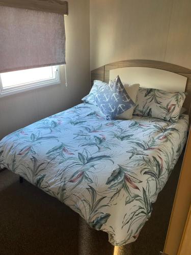a bedroom with a bed with a floral comforter at BrookeView Caravan Rental, Seton Sands in Port Seton