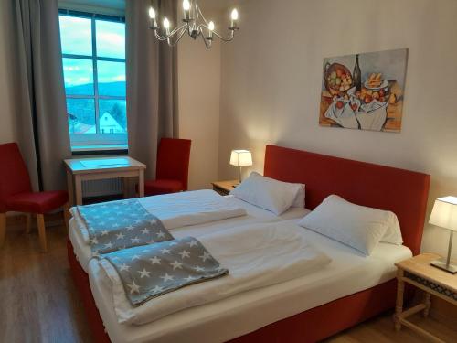 a bedroom with a large bed with two red chairs at Hotel-Gasthof Opel in Heinersreuth