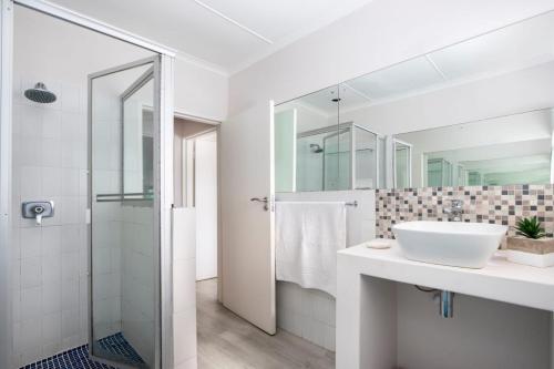 a white bathroom with a sink and a shower at Onrus Cottage in Hermanus