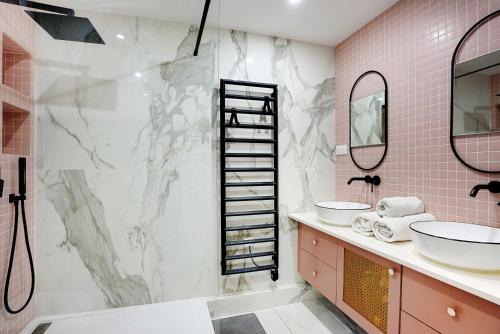 baño con 2 lavabos y ducha con azulejos rosados en Modern spacious apartment just outside Paris, en Levallois-Perret