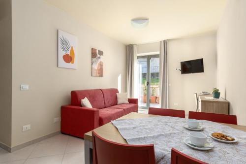 a living room with a table and a red chair at Tuscasì Aparthotel in Sovicille