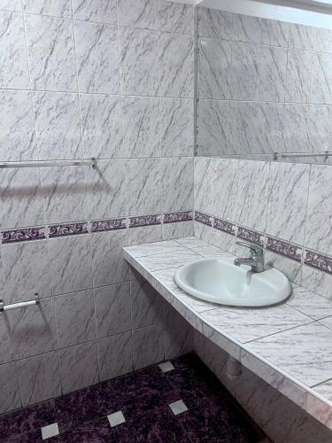 a bathroom with a sink and a marble wall at América inn in Puno