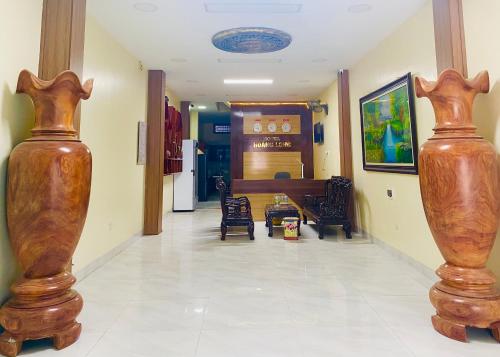 a hallway with two large wooden vases on the floor at HOTEL HOÀNG LONG in Diện Biên Phủ