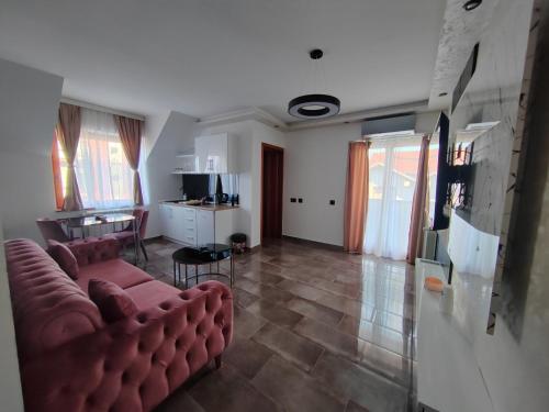 uma sala de estar com um sofá e uma mesa em Hedonic Wellness Apartmani em Niš
