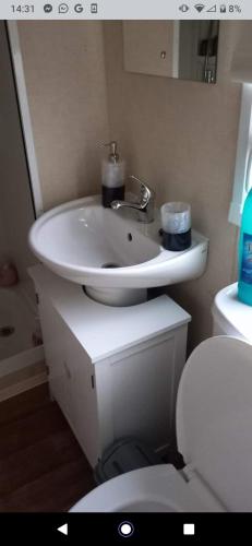 ein Badezimmer mit einem weißen Waschbecken und einem WC in der Unterkunft Deluxe 3 bedroom Lyons Robin hood oaklands with free wifi free sky in Meliden