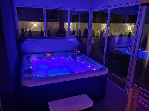 uma banheira com iluminação roxa num quarto em Hedonic Wellness Apartmani em Niš