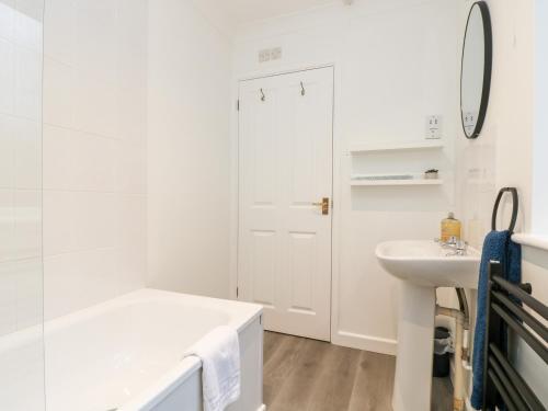 La salle de bains blanche est pourvue d'une baignoire et d'un lavabo. dans l'établissement Chellowdene Cottage, à Falmouth