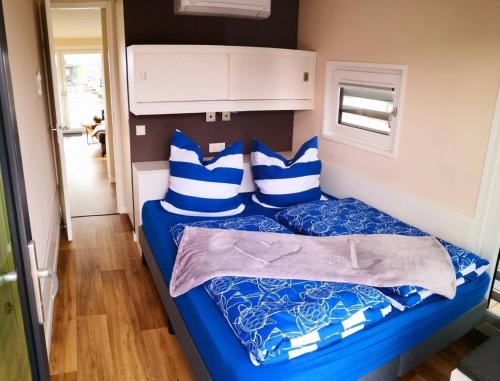 a small bedroom with a blue bed with blue and white pillows at Hausboot Schatzinsel in Klitten