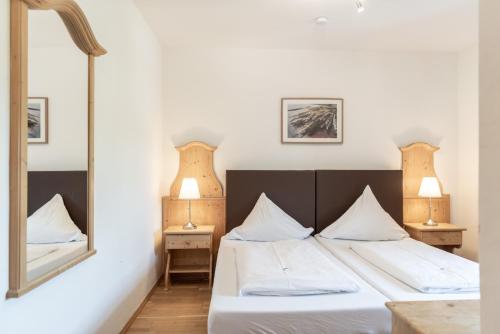 a bedroom with a bed with white sheets and a mirror at Hotel Stanglbräu 