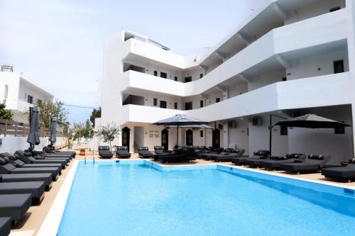 een hotel met een zwembad en ligstoelen bij Penélope Hotel in Ialyssos