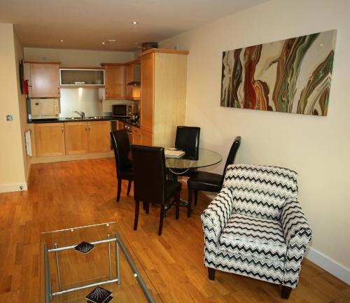 a living room with a table and chairs and a kitchen at The Grove - Properties Unique in Newcastle upon Tyne