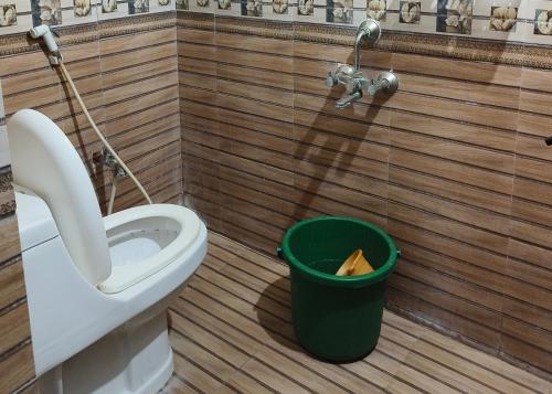 a bathroom with a toilet and a green trash can at V1 Stay Home in Tirupati