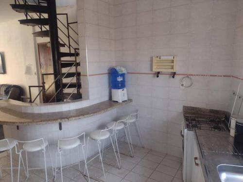 a kitchen with a counter and stools in a room at Cobertura duplex piscina churras e 2 vagas super arejado in Mongaguá
