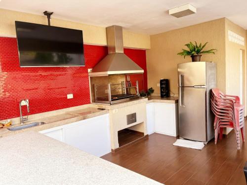 uma cozinha com um frigorífico e uma parede vermelha em CASA TEMPORADA COM PISCINA PRIVATIVA no Guarujá