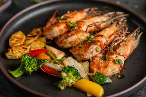 a plate of food with shrimp and vegetables on a table at Fushifaru Maldives with 50 percent off on sea plane roundtrip 04 nights & above in Fushifaru