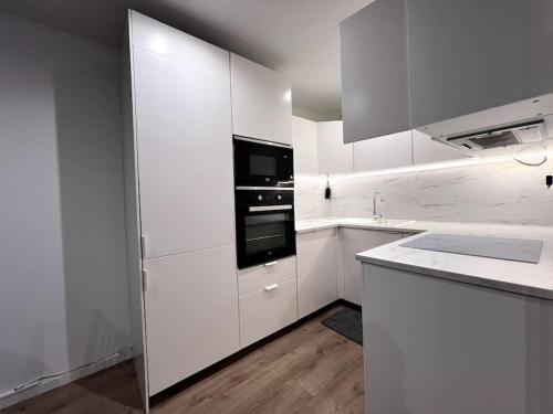- une cuisine blanche avec des placards blancs et un four noir dans l'établissement Logement-Proche Strasbourg-rez de jardin-Centre, à Strasbourg