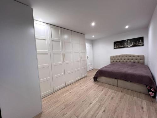 - une chambre avec un lit, des murs blancs et du parquet dans l'établissement Logement-Proche Strasbourg-rez de jardin-Centre, à Strasbourg