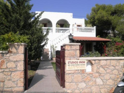a white house with a stone fence and a sign at Studios Irene in Skala
