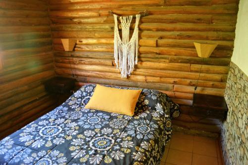 1 dormitorio con 1 cama en una cabaña de madera en Kpriccio Cabanas en Potrerillos