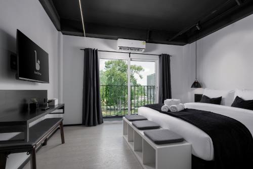 BedTime Hotel Samui في شاطئ تشاوينغ: غرفة نوم مع سرير مع مكتب ونافذة