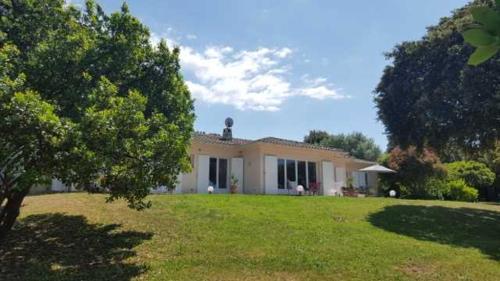 une maison dans une cour avec une pelouse verte dans l'établissement A MERENDELLA, villa avec vaste jardin arboré, vue mer, accès direct plage, à Pietrosella