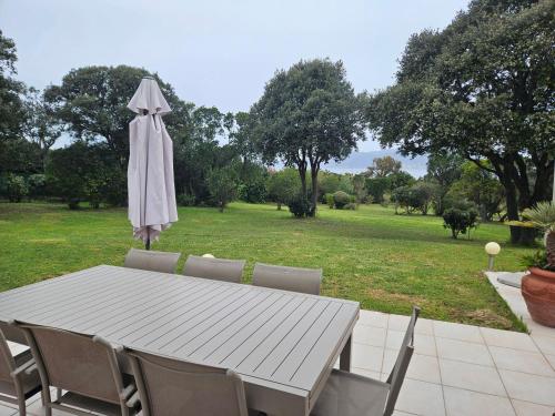 une table blanche avec des chaises et un parasol dans l'établissement A MERENDELLA, villa avec vaste jardin arboré, vue mer, accès direct plage, à Pietrosella