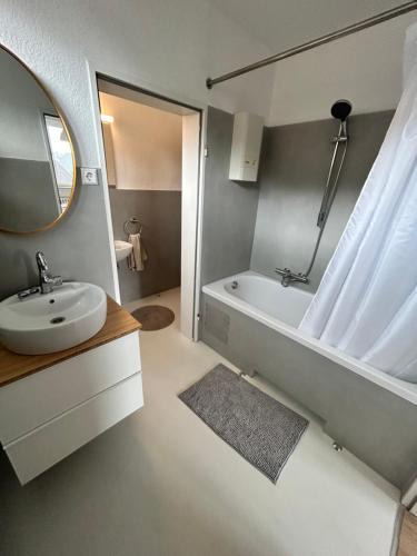 een badkamer met een bad, een wastafel en een spiegel bij geräumige Ferienwohnung Emsaue in Rheine