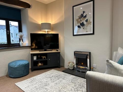 a living room with a television and a fireplace at Three - Yard 12 in Kendal