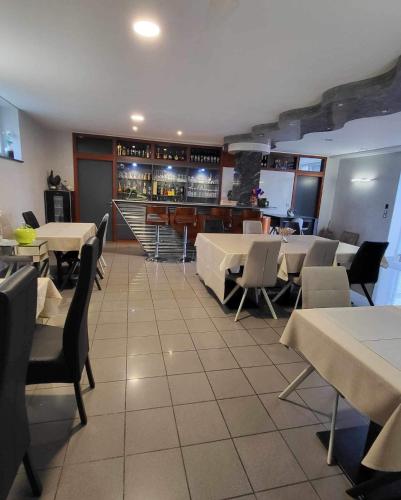 a restaurant with tables and chairs and a bar at les charmes de la vallée noble in Soultzmatt