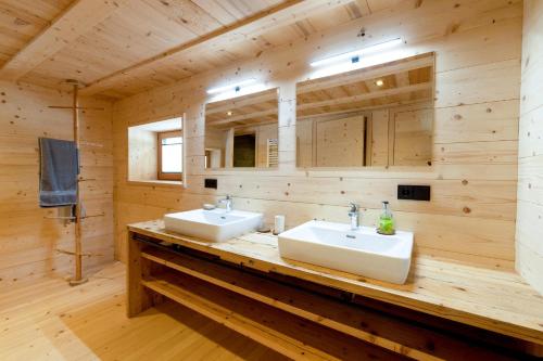 - une salle de bains avec deux lavabos dans une chambre en bois dans l'établissement Haus Greates, à Forchach