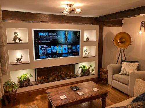 uma sala de estar com lareira e uma televisão de ecrã plano em River Avon Retreat - A Rustic Gem On The Riverbank em Fordingbridge