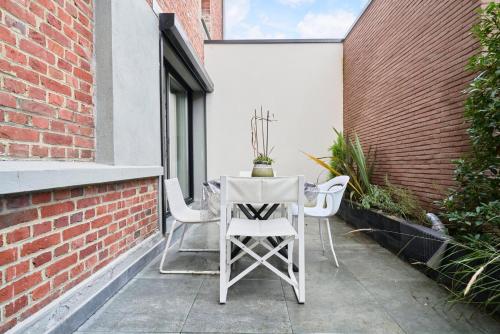 une table blanche et des chaises sur une terrasse dans l'établissement 2 bedroom apartment w/ courtyard at Croisé Laroche, à Marcq-en-Barœul
